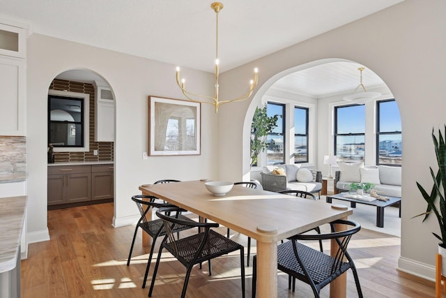 dining area with light wood-type flooring and a notable chandelier