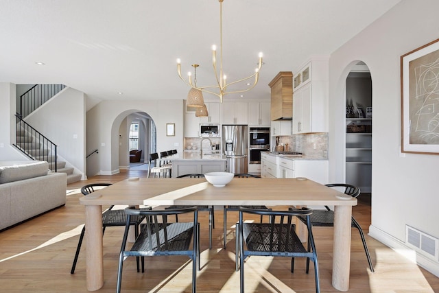 dining room with a notable chandelier, light hardwood / wood-style floors, and sink