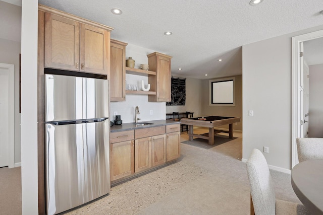 kitchen featuring sink, a textured ceiling, light brown cabinets, billiards, and stainless steel fridge