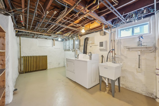 basement featuring radiator heating unit, electric panel, and washing machine and dryer