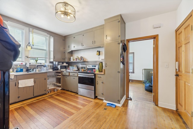 kitchen featuring radiator, light hardwood / wood-style flooring, stainless steel appliances, and a chandelier