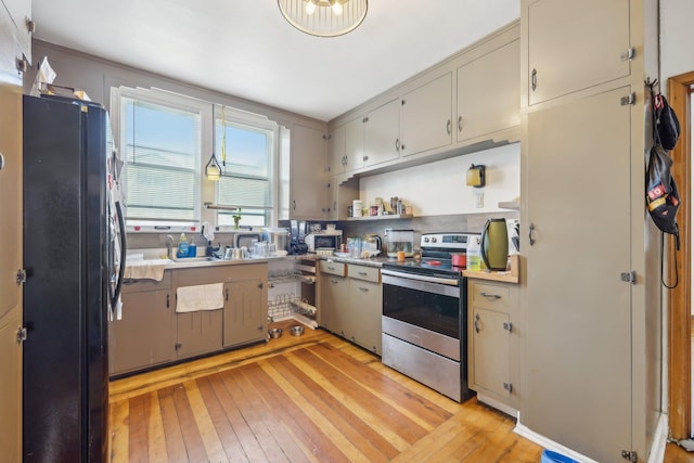 kitchen featuring light wood-type flooring, black fridge, and stainless steel electric range