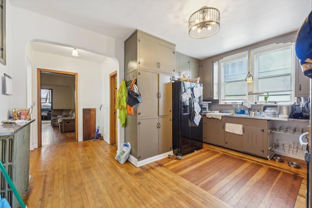 kitchen featuring a notable chandelier, light wood-type flooring, black fridge with ice dispenser, and gray cabinets