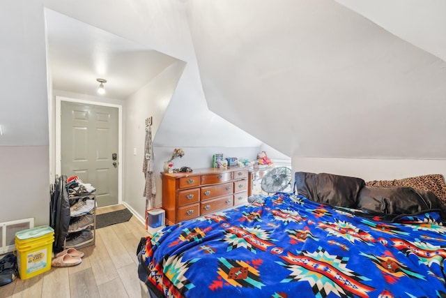 bedroom with light wood-type flooring and vaulted ceiling