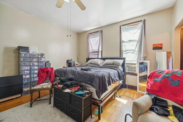 bedroom featuring wood-type flooring, cooling unit, and ceiling fan