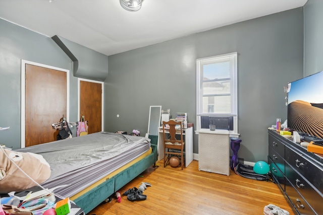 bedroom with cooling unit and light hardwood / wood-style flooring