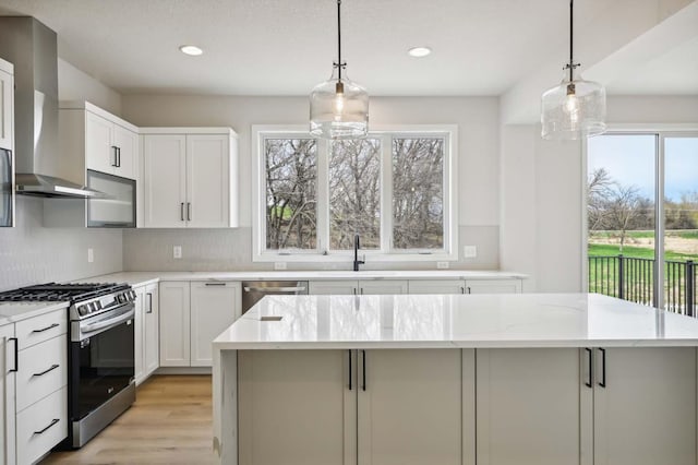 kitchen featuring white cabinetry, wall chimney range hood, stainless steel appliances, and a kitchen island