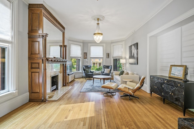 living area featuring light hardwood / wood-style floors, an inviting chandelier, crown molding, and a premium fireplace