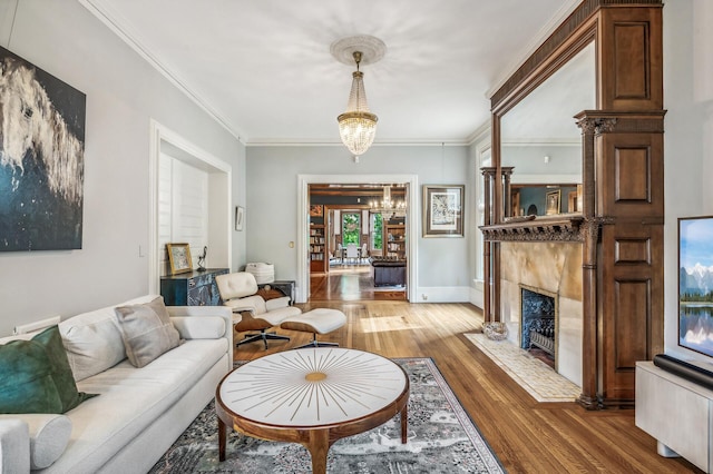 living room with a notable chandelier, wood-type flooring, a fireplace, and ornamental molding