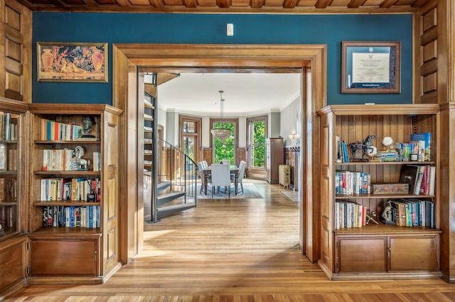 corridor featuring light hardwood / wood-style floors, ornamental molding, and wood ceiling