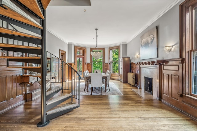 dining area featuring a notable chandelier, radiator heating unit, wood-type flooring, and ornamental molding