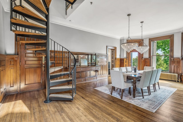 dining room featuring hardwood / wood-style flooring, ornamental molding, radiator, and a chandelier