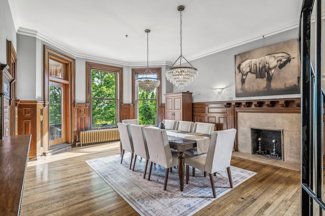 dining room featuring radiator heating unit, ornamental molding, a notable chandelier, and hardwood / wood-style flooring