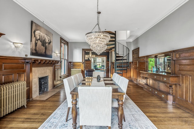 dining space with dark hardwood / wood-style flooring, radiator, ornamental molding, and a tiled fireplace