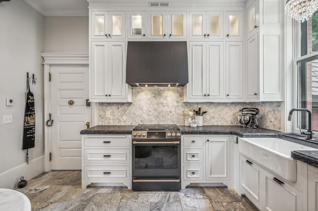 kitchen featuring gas range, white cabinets, and wall chimney range hood