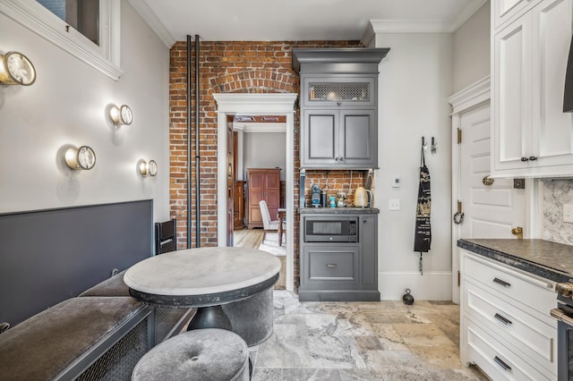 kitchen with ornamental molding, white cabinetry, stainless steel microwave, and gray cabinetry