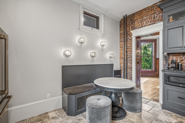 dining area featuring ornamental molding and brick wall