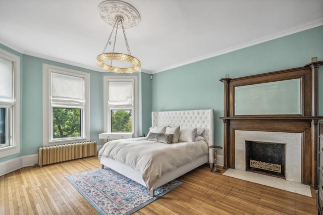 bedroom featuring a fireplace, hardwood / wood-style flooring, radiator, and crown molding