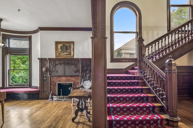 stairs featuring a wealth of natural light, wood-type flooring, and ornamental molding