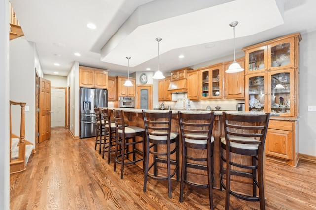 kitchen with a spacious island, light wood-type flooring, decorative light fixtures, and stainless steel appliances