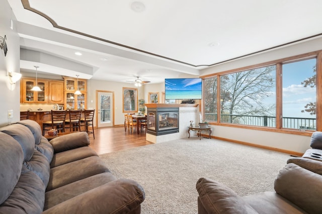 living room featuring light wood-type flooring, ceiling fan, and a multi sided fireplace