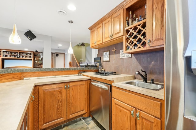 kitchen featuring appliances with stainless steel finishes, decorative light fixtures, tasteful backsplash, sink, and kitchen peninsula