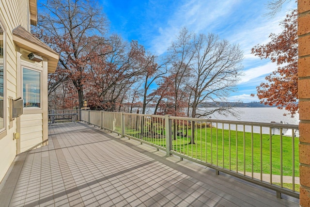 wooden deck featuring a water view and a lawn