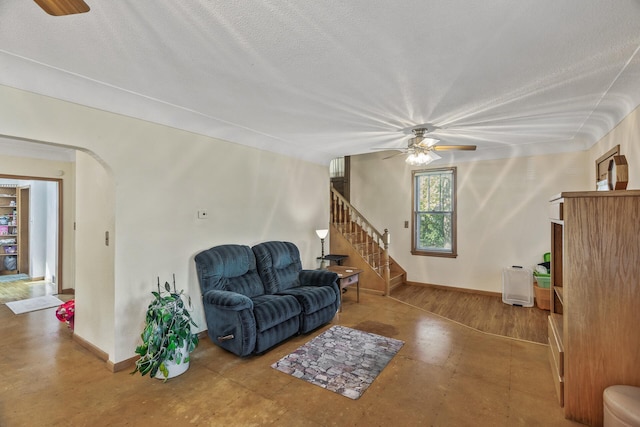 living room featuring ceiling fan, a textured ceiling, and wood-type flooring