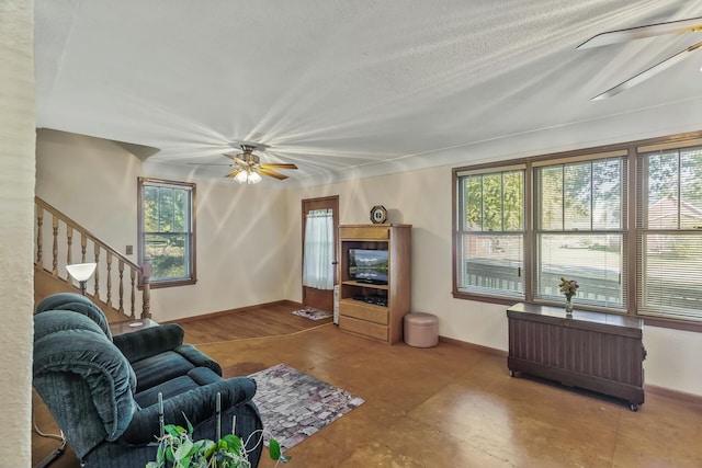 living room with a textured ceiling, ceiling fan, and a wealth of natural light