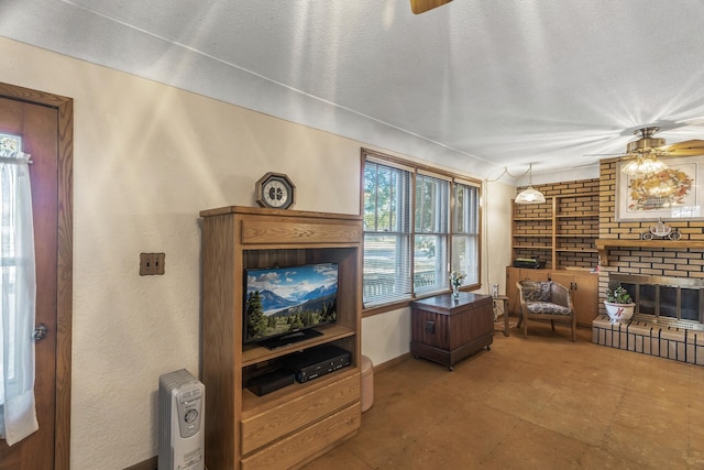 living room featuring ceiling fan, a textured ceiling, a brick fireplace, and built in shelves