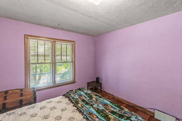 bedroom with hardwood / wood-style flooring and a textured ceiling