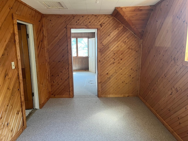 bonus room featuring light carpet and wood walls