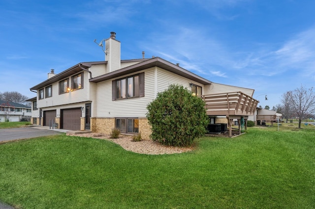 back of house featuring a garage, a lawn, and central AC