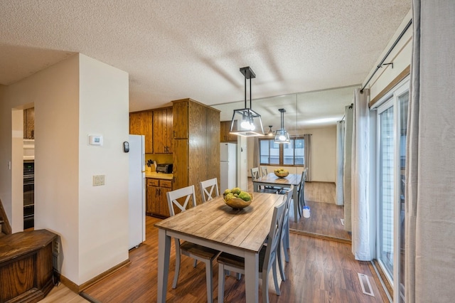 dining space with hardwood / wood-style flooring and a textured ceiling