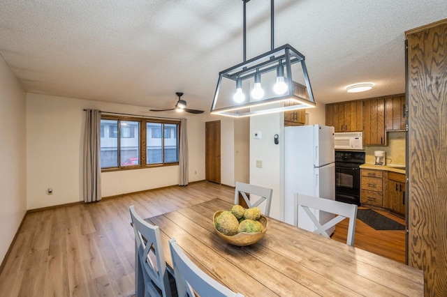 dining area featuring a textured ceiling, light wood-type flooring, and ceiling fan