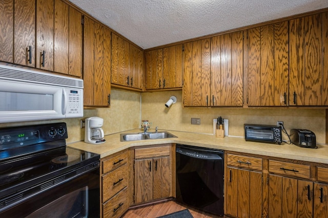 kitchen featuring a textured ceiling, light hardwood / wood-style flooring, black appliances, and sink