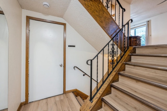 staircase with a textured ceiling and hardwood / wood-style flooring