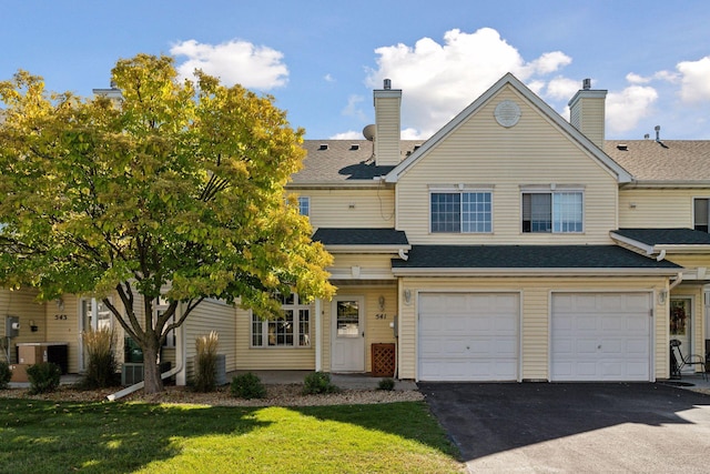 view of front of property with cooling unit, a front yard, and a garage