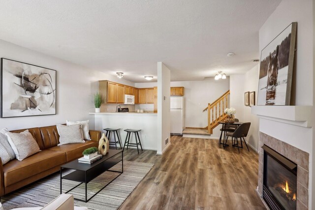 living room featuring a tiled fireplace, a textured ceiling, and dark hardwood / wood-style flooring