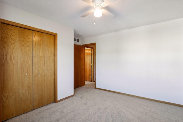 unfurnished bedroom with ceiling fan, light colored carpet, a textured ceiling, and a closet