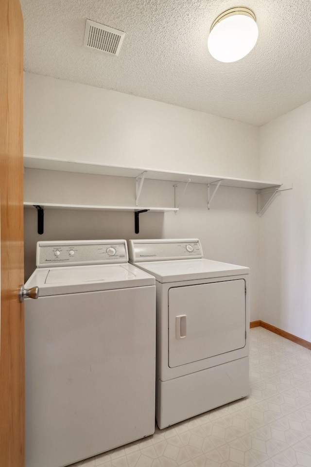 laundry area featuring a textured ceiling and washer and dryer