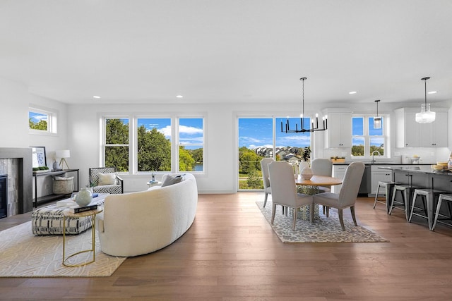 living room with an inviting chandelier, hardwood / wood-style floors, sink, and plenty of natural light