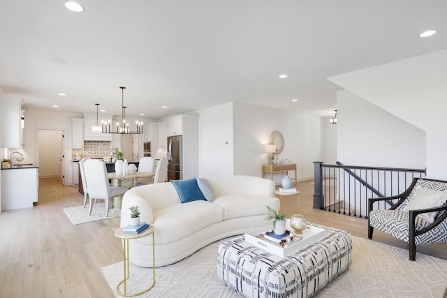 living room with light hardwood / wood-style flooring, a chandelier, and sink