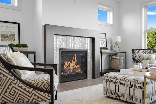 bedroom featuring a towering ceiling, light hardwood / wood-style floors, multiple windows, and a fireplace