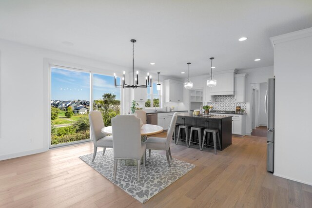 dining area with light wood-type flooring, sink, and a chandelier