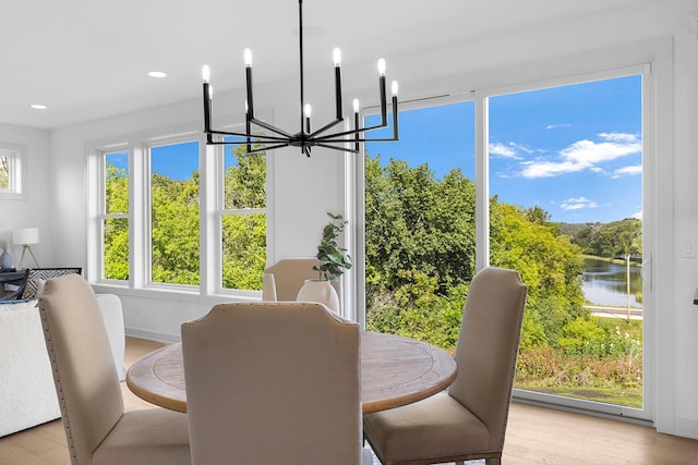 dining area featuring a notable chandelier, light wood-type flooring, and a water view