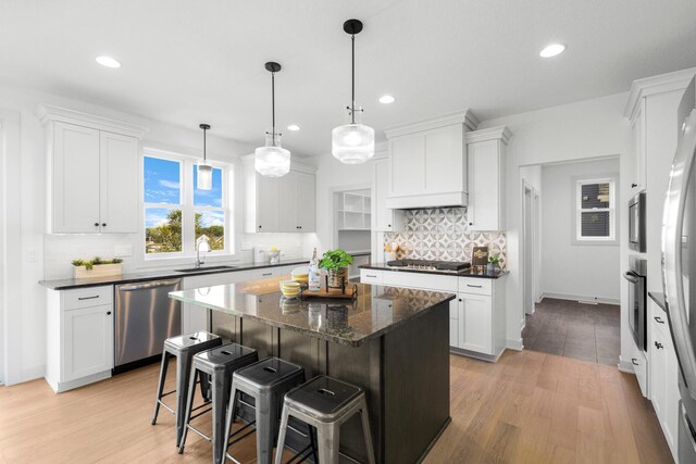 kitchen featuring stainless steel appliances, white cabinets, light hardwood / wood-style floors, and a center island