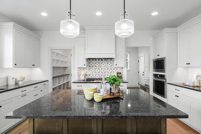 kitchen featuring decorative light fixtures, stainless steel appliances, and white cabinets