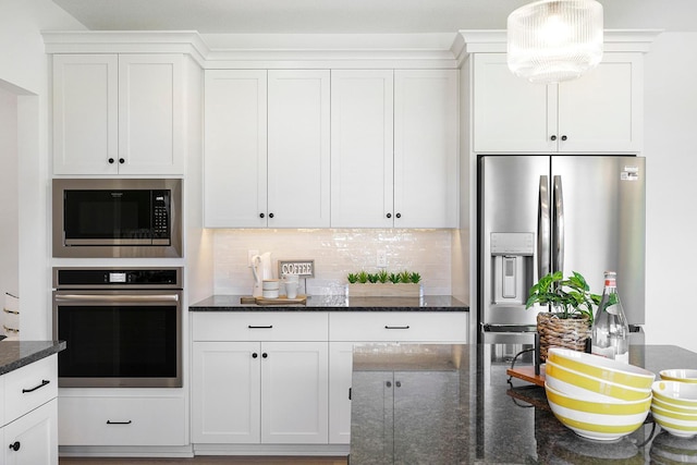 kitchen with stainless steel appliances, white cabinetry, and dark stone countertops