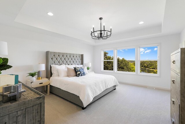 bedroom with carpet flooring, a tray ceiling, and a notable chandelier